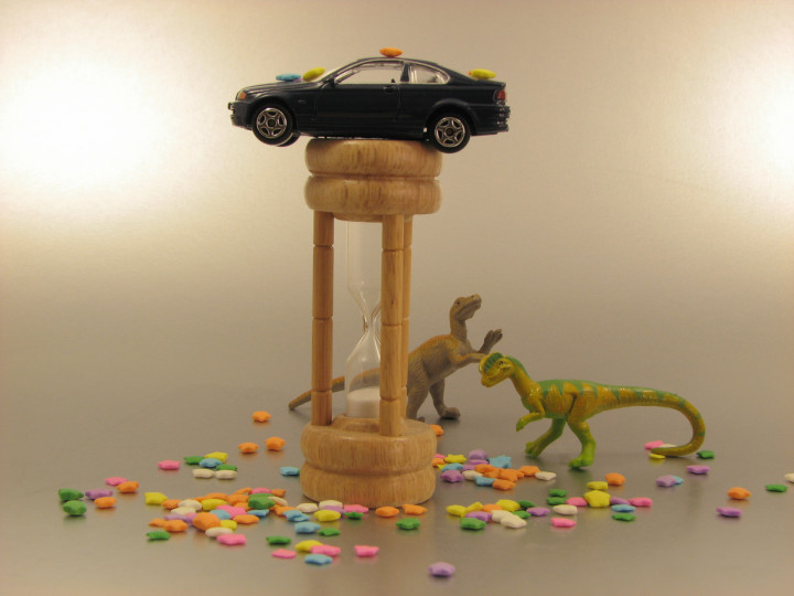 Photo of
                an hour glass, toy dinosaur models, and a toy
                automobile
