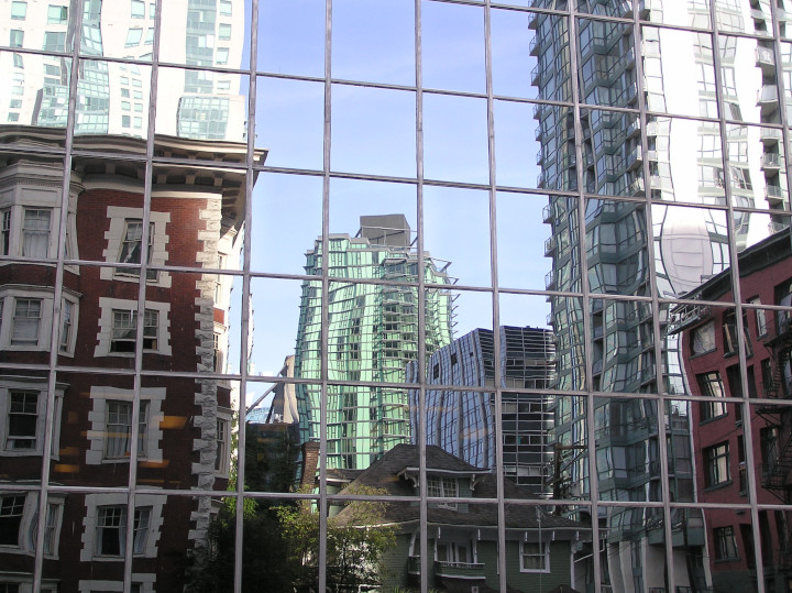 Photo of a
                reflected and distorted city view with buildings old and
                new