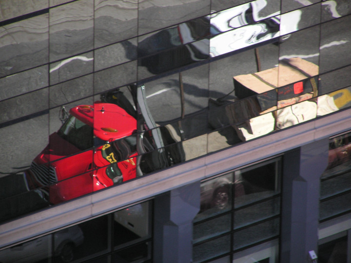 Photo of
                vehicles distorted in building window reflections